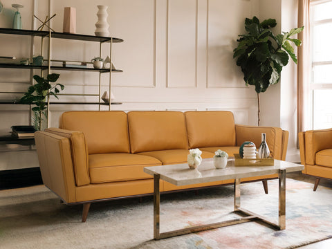 Stylish living room featuring mid-century leather sofas with a chic coffee table, plants, and modern decor for a cozy aesthetic.