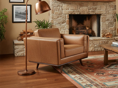 Selina Midcentury Tan Leather Accent Chair in a stylish living room with a stone fireplace and oriental rug.