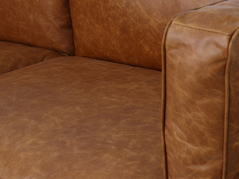 Close-up of Eleganza Cognac Distressed Leather 3 Seater Sofa with plush loose cushions and full top aniline leather texture.