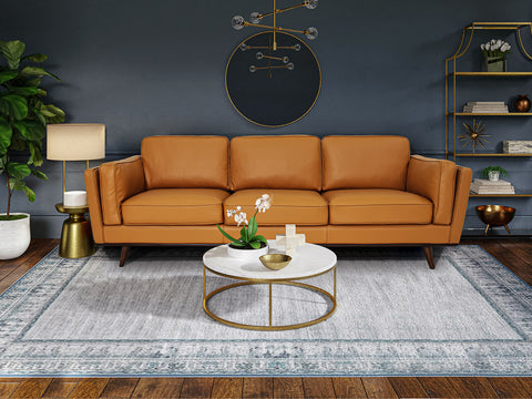 Selina Midcentury Cognac Leather 3 Seater Sofa in a modern living room setting with a round coffee table.