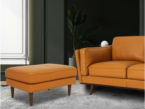 Selina Midcentury Cognac Leather Ottoman paired with a modern sofa in a stylish living room setting.