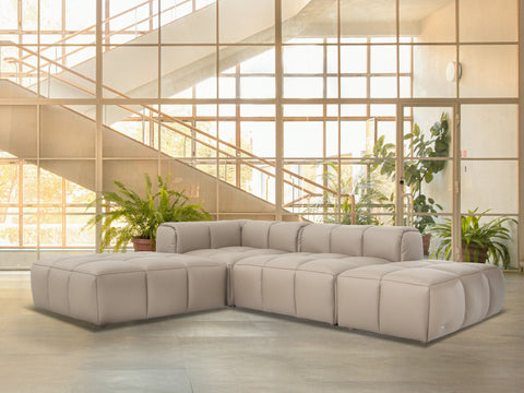 Tuscono Beige Leather Low Profile Modular Sofa in a modern setting with lush greenery and natural light.