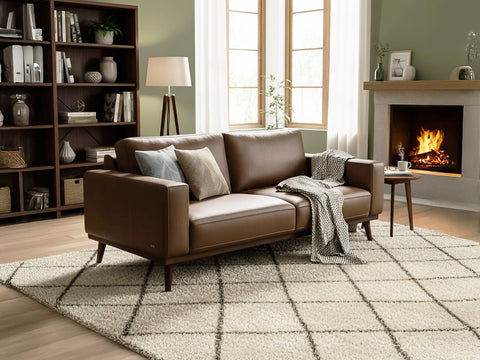 Cozy living room with leather sofa and fireplace, showcasing The Cozy Luxury Trend.