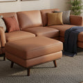 Selina Midcentury Brown Leather Ottoman in living room setting with cozy couch and pillows, showcasing stylish and comfortable decor.