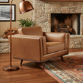 Selina Midcentury Tan Leather Accent Chair in a stylish living room with a stone fireplace and oriental rug.