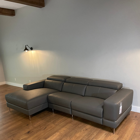 Gray sectional sofa in a room with wooden flooring and a light gray wall.