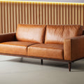 Luxury Amore Cognac Distressed Leather 3 seater sofa with teak oak legs in modern living room setting.