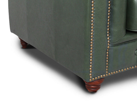 Close-up of the Stanhope Royal Green Leather 4 Seater Chesterfield corner with nailhead trim and wooden legs.