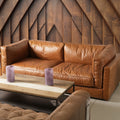 Eleganza Cognac Distressed Leather 3 Seater Sofa with walnut legs against a wooden paneled wall