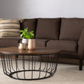 Sogno Round Wood Top Metal Caged Base Coffee Table in a living room with a brown sofa and decorative items on the table.