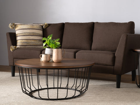 Sogno Round Wood Top Metal Caged Base Coffee Table in a living room with a brown sofa and decorative items on the table.