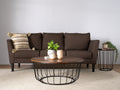 Living room scene with Sogno Round Wood Top Metal Caged Base Coffee Table in front of brown sofa and side table.